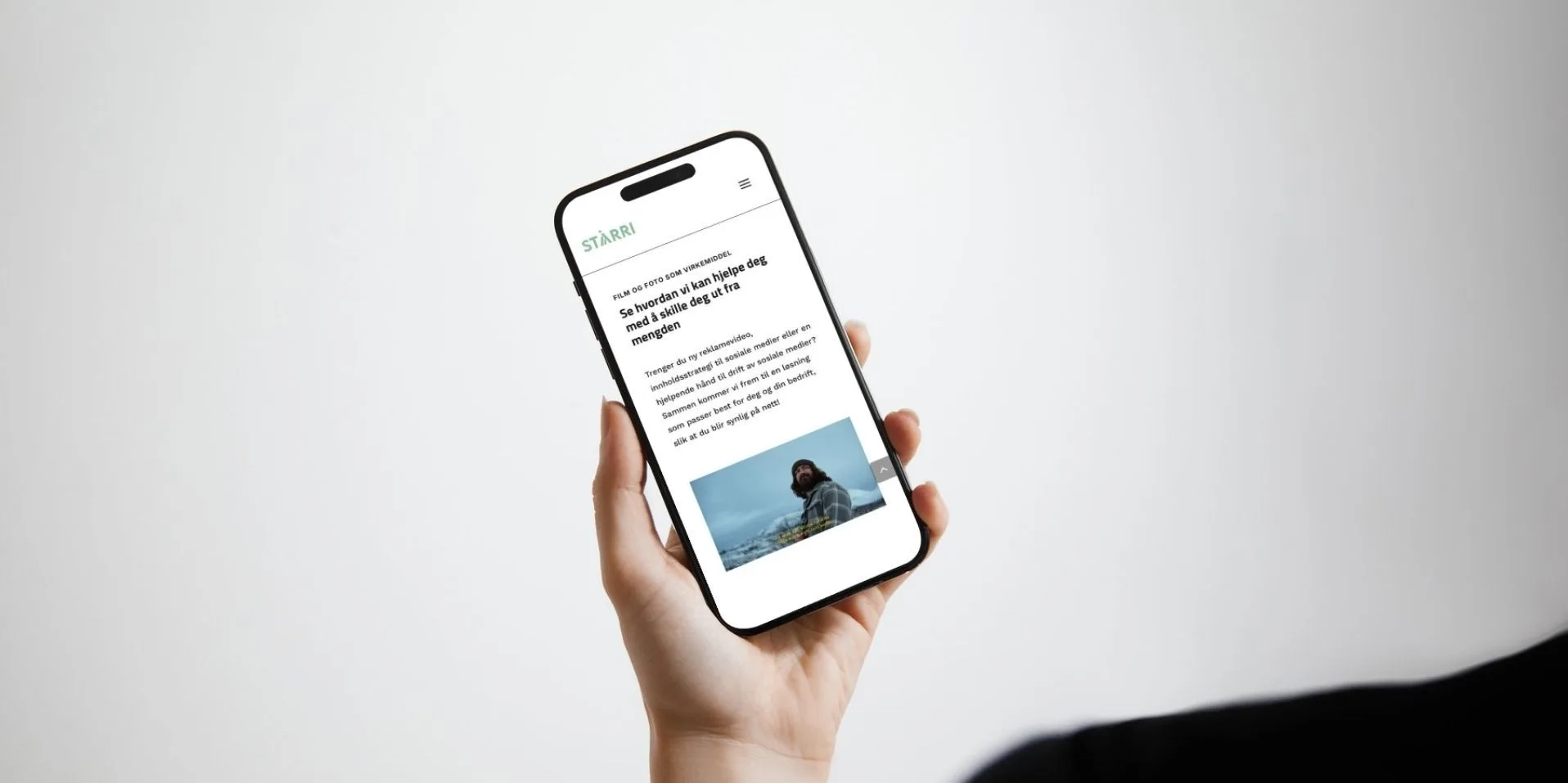 Hånd som holder en Iphone for å vise frem en nettside